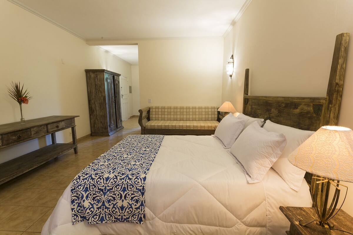 Ein Schlafzimmer mit einem großen Bett, einer Bank, einem Sofa und einem Kleiderschrank.