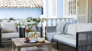 Un espacio exterior acogedor con mobiliario de mimbre, una mesa de centro de madera y un jarrón decorativo con flores.