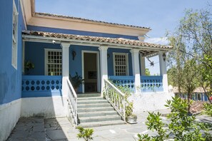 Un edificio de dos pisos con fachada azul, adornos blancos y techo de tejas.