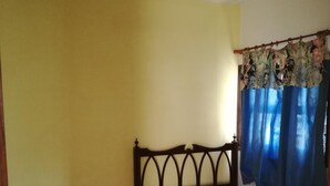 A bedroom with a bed, a small table with a lamp, and a window with curtains. - Casa Banana - Holiday home on the coast with views (Tazacorte)