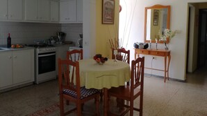 A kitchen with white cabinets, a stove, and a dining table with chairs. There is a mirror on the wall and a vase with flowers on the table. - Casa Banana - Holiday home on the coast with views (Tazacorte)