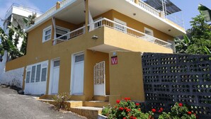A two-story building with a yellow facade, white balconies, and a gated entrance. - Casa Banana - Holiday home on the coast with views (Tazacorte)