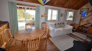 Una habitación acogedora con una mesa de comedor de madera, un sofá blanco y una escalera.