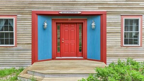 A house with a red door, a blue door frame, and a sign that reads "BACH PLUM HOUSE".