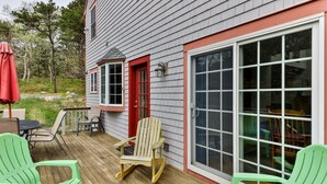A wooden deck with outdoor seating, a rocking chair, and a large sliding glass door.