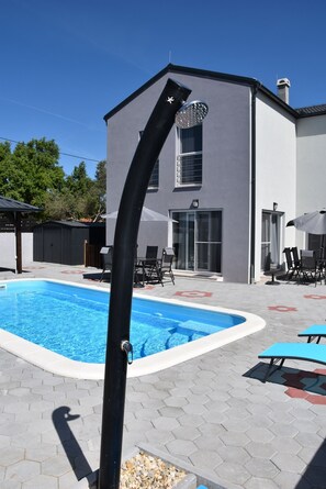 A swimming pool with a black pole, hexagonal tiles, and a building with a gray facade and a window. - Villa Luna - with a pool, hot tub, infrared sauna, fitness center, amusement park, the ocean, and a lake (Biograd na Moru)