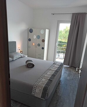A bedroom with a bed, a wardrobe with circular patterns, a bedside lamp, and a view of greenery outside. - Villa Luna - with a pool, hot tub, infrared sauna, fitness center, amusement park, the ocean, and a lake (Biograd na Moru)