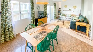 A dining area with a wooden table and green chairs, a sofa, and a TV in the background. - Suite Natura @ Casa del Lago (Puerto de la Cruz)