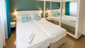 Une chambre d’hôtel avec deux lits, un grand miroir et une vue sur la mer.