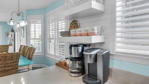 A kitchen with a coffee maker, a toaster, and a shelf with cups. - Palm Place, Spacious beach house steps to the powdery sand and emerald water. (Destin)