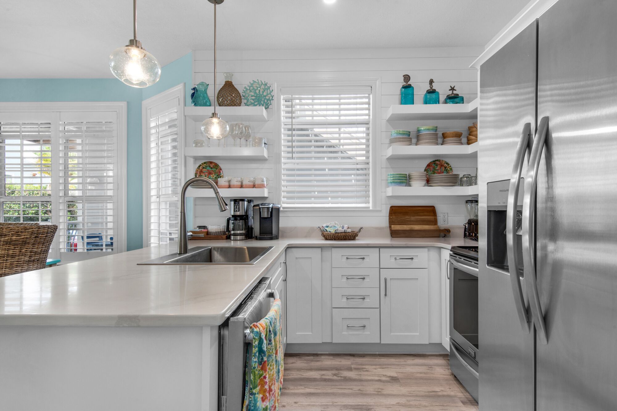 A modern kitchen with white cabinetry, a stainless steel refrigerator, and a central island with a sink.