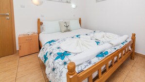 Un llit ben fet amb roba de llit floral, un panell de fusta i una tauleta de nit amb una làmpada.