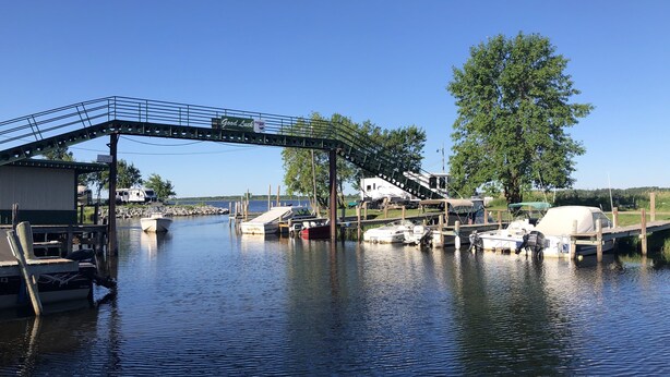 Un port de plaisance avec des bateaux amarrés, un pont et une remorque en arrière-plan.