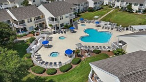 A large outdoor swimming pool surrounded by lounge chairs and umbrellas, with a white fence and well-maintained lawns. - Sandpiper Unit 4209/Beach Service/Gated Cmty/Reserved Parking/Many Amenities!!!! (Destin)
