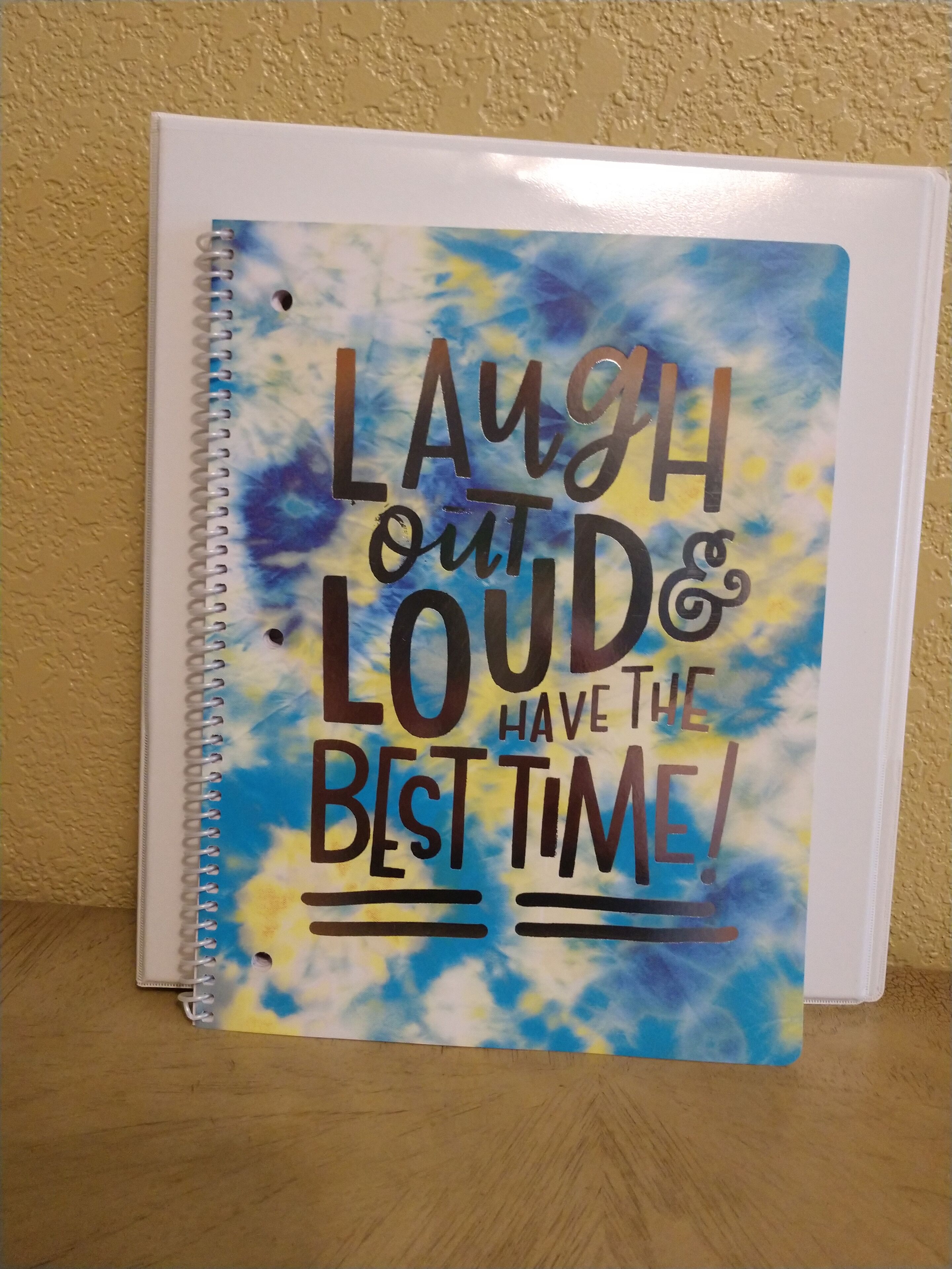 A notebook with a motivational quote on a tie-dye background.