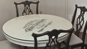 Un coin repas comprenant une table ronde, quatre chaises, un lustre, une horloge et une porte.