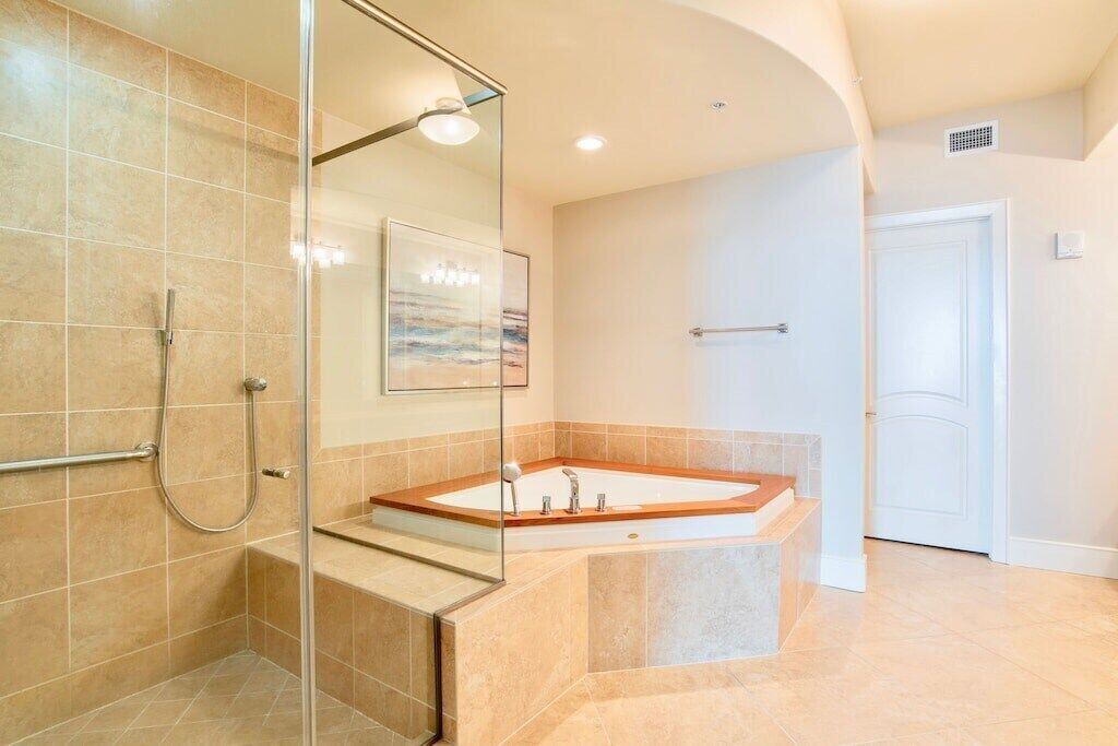 Un baño moderno con cabina de ducha de vidrio, una bañera independiente y una puerta blanca.