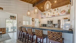 A kitchen with a bar area, wooden ceiling, and a mural. - Recovery Room | 300 ft from the beach | Private Pool, Hot Tub, Dog Friendly (Virginia Beach)