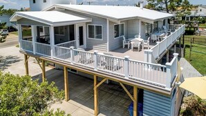 A two-story house with a covered patio and outdoor seating area. - Recovery Room | 300 ft from the beach | Private Pool, Hot Tub, Dog Friendly (Virginia Beach)