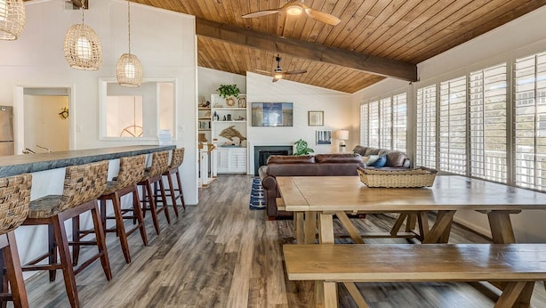 A spacious kitchen with a long counter and bar stools, a wooden ceiling, and large windows. - Recovery Room | 300 ft from the beach | Private Pool, Hot Tub, Dog Friendly (Virginia Beach)