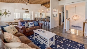 A spacious living area with a leather sofa, a white coffee table, and nautical-themed decor. - Recovery Room | 300 ft from the beach | Private Pool, Hot Tub, Dog Friendly (Virginia Beach)