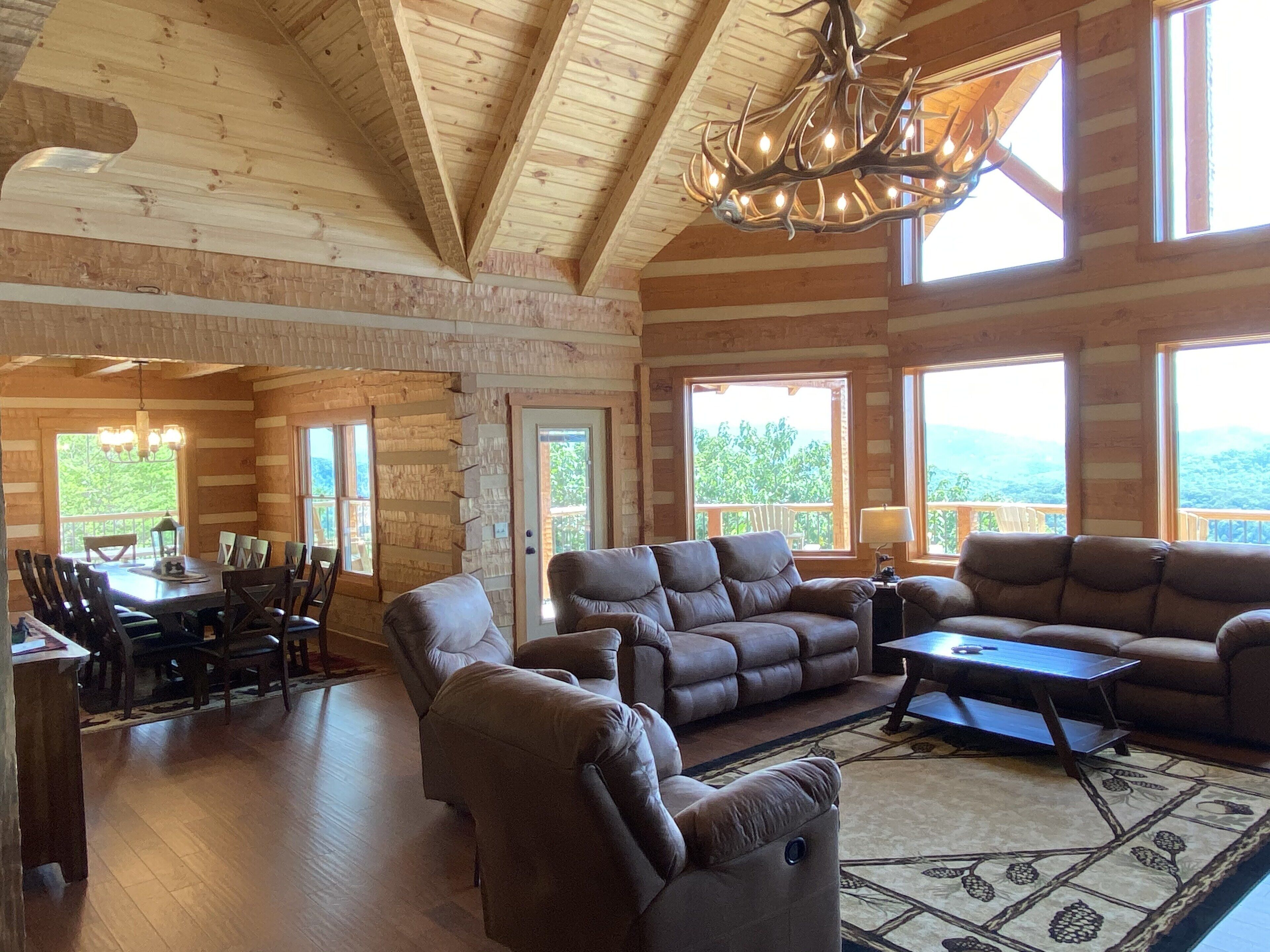 A spacious living room with a fireplace, large windows, and a dining area with a table and chairs.
