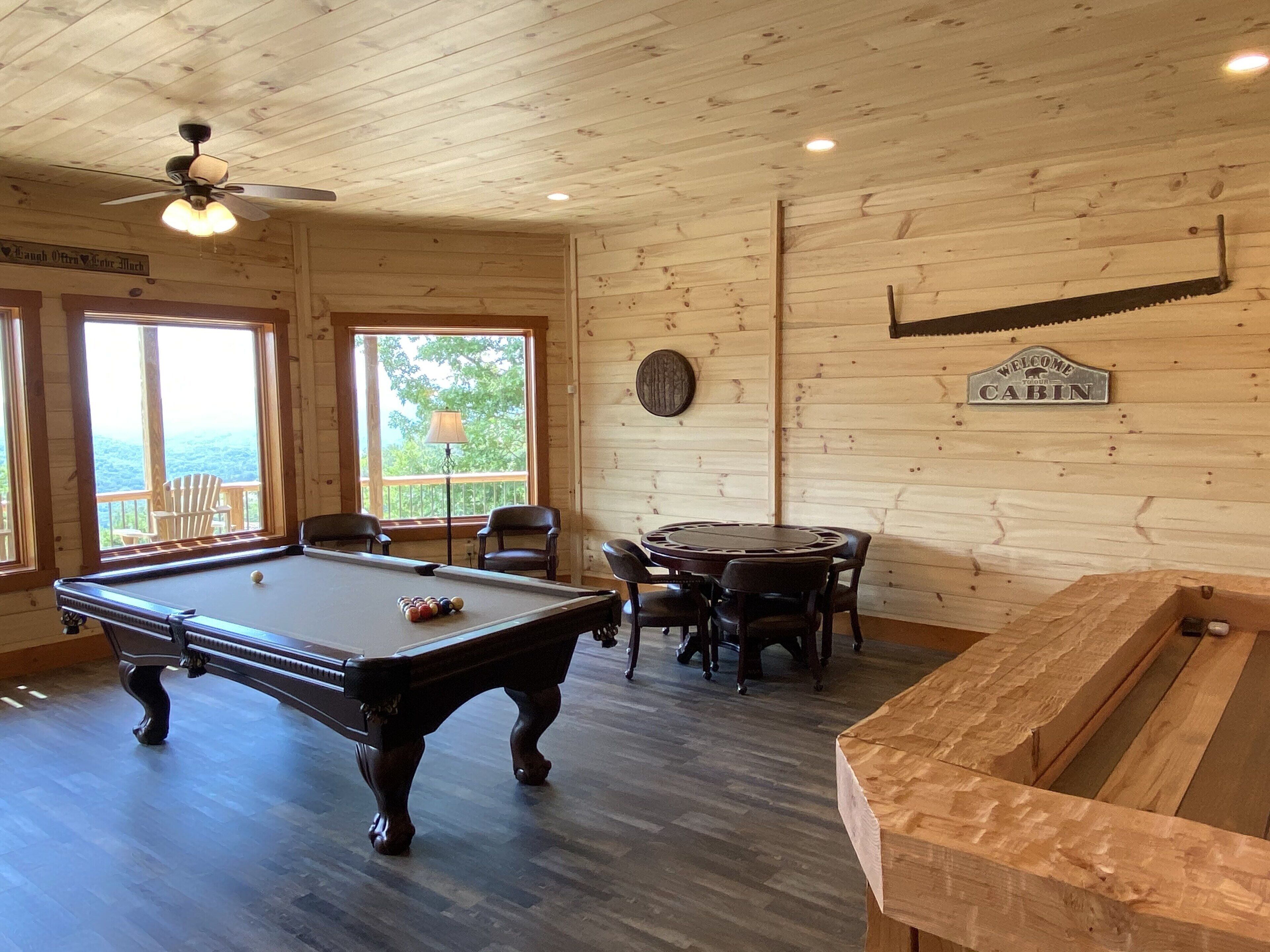 Una cabaña de madera con mesa de billar, sillas y un letrero que dice 'Welcome to Cabin'.