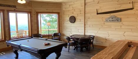Una cabaña de madera con mesa de billar, sillas y un letrero que dice 'Welcome to Cabin'.