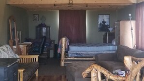 Un salon chaleureux avec un plafond haut, des poutres apparentes, un canapé, une table basse et un téléviseur.