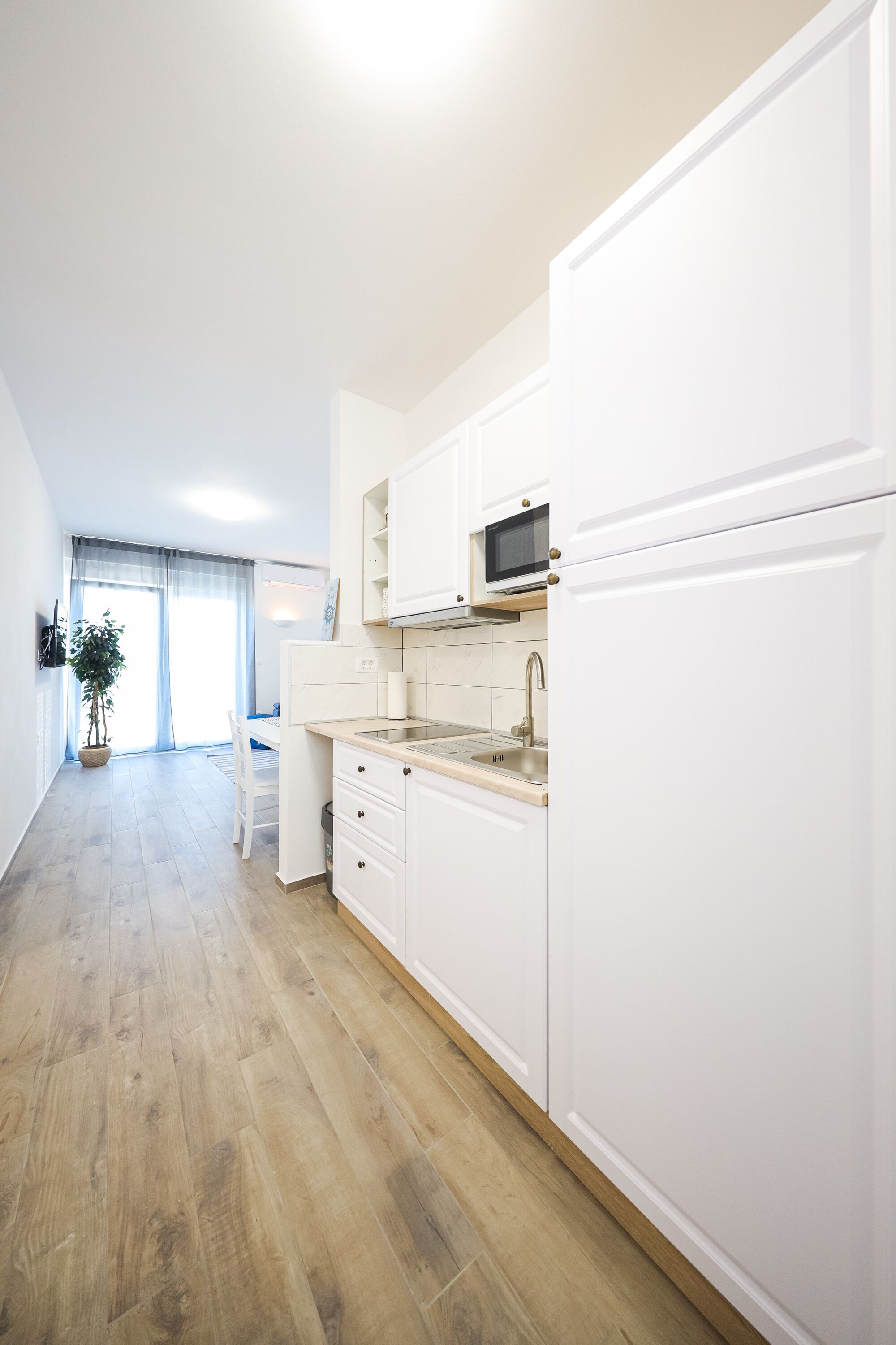 Une cuisine moderne avec des meubles blancs, un four à micro-ondes et un évier.