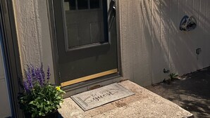 Uma porta de entrada com um pequeno degrau, uma caixa de correio e um luminário fixado na parede.