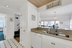 Enjoy cooking in this well-equipped kitchen with a granite countertop, stainless steel sink, and white cabinetry.