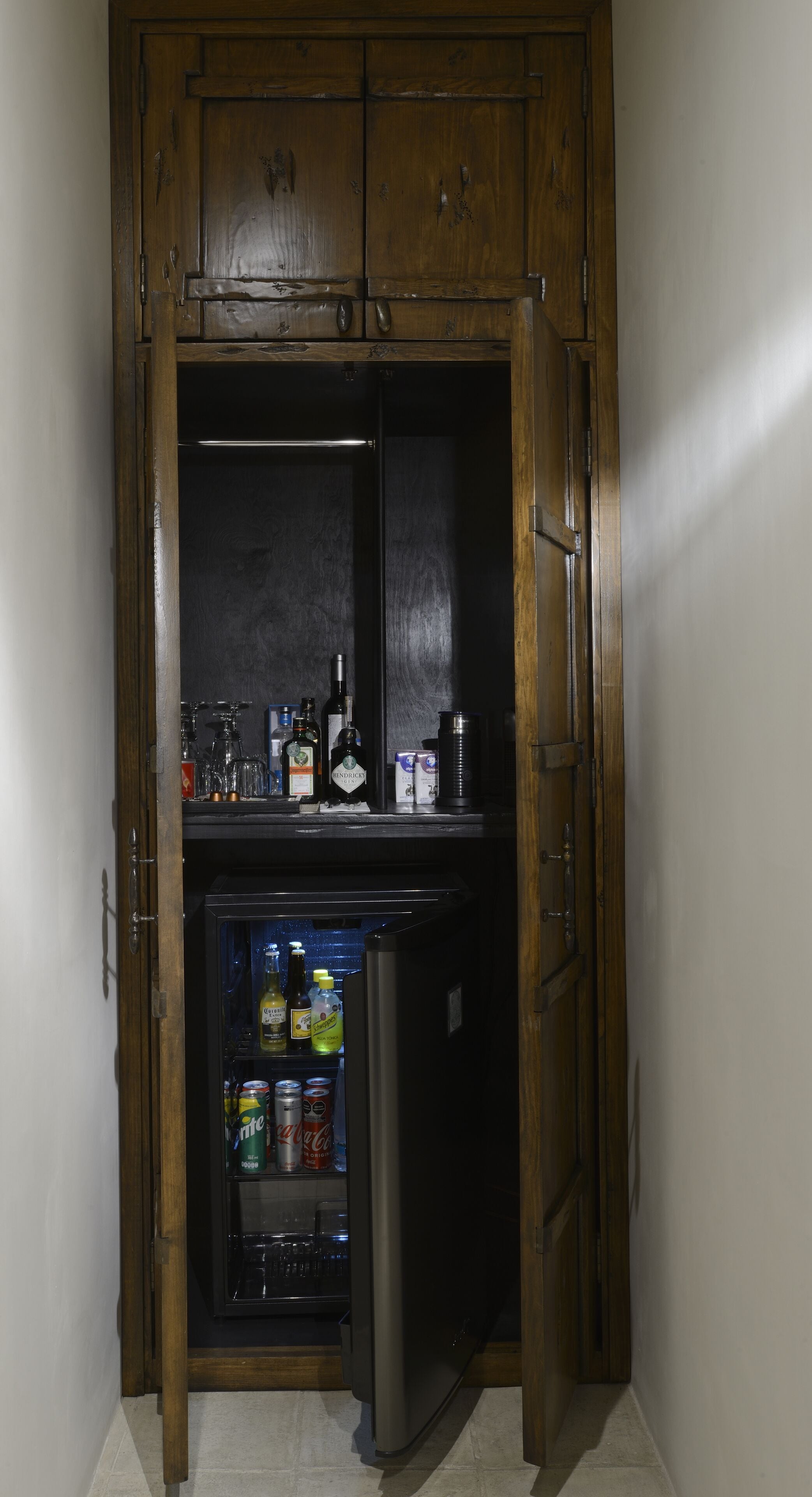 Ein kompakter Kühlschrank mit einer darüber angebrachten Holzkabine, gefüllt mit verschiedenen Getränken und Konservendosen.