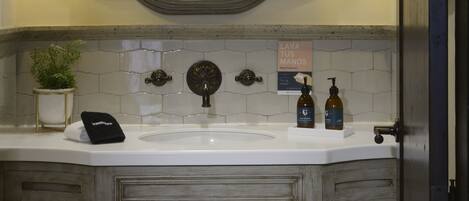 A bathroom with a large mirror, two wall-mounted lamps, a sink, and a cabinet with two doors.