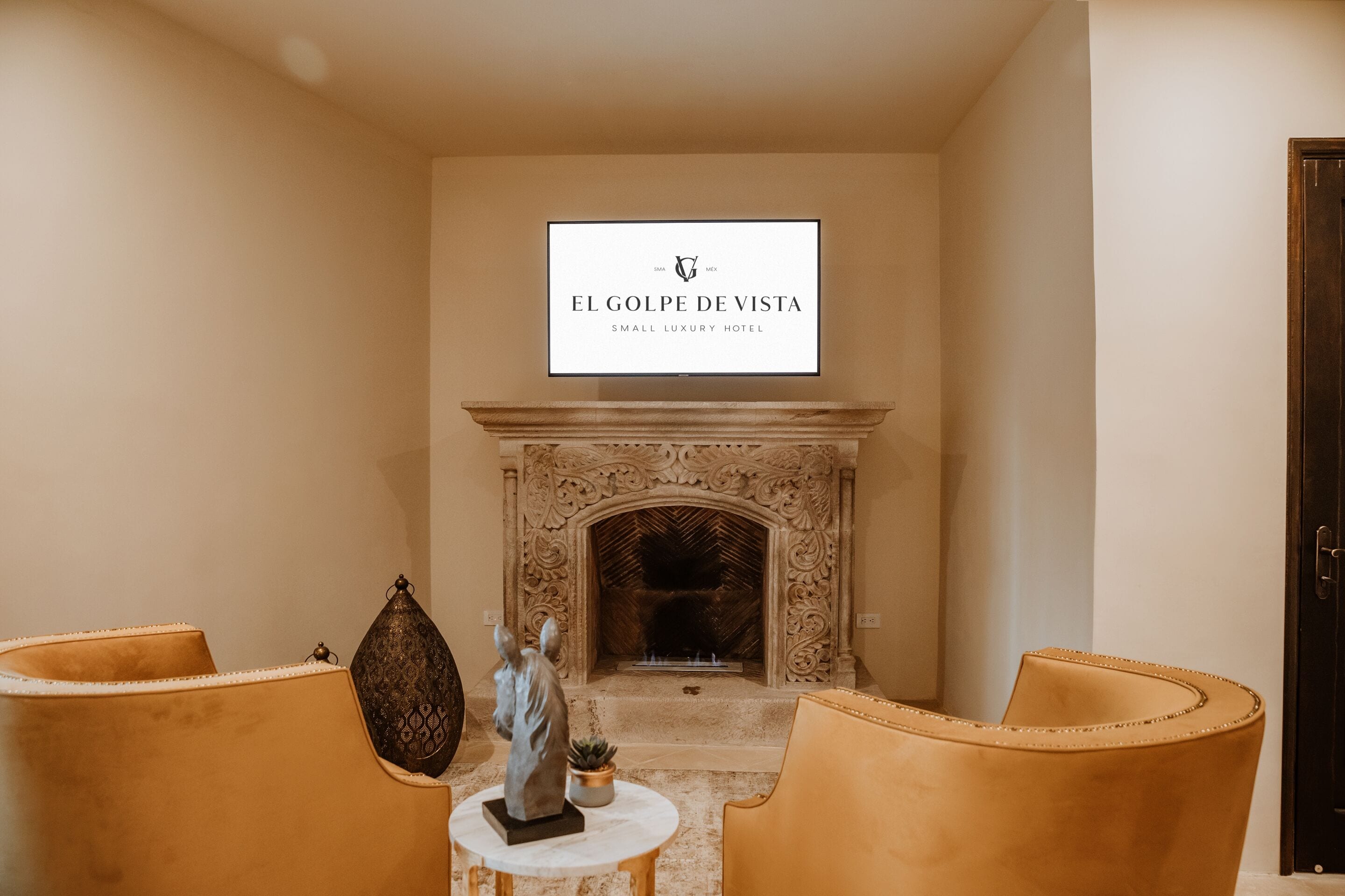 L’intérieur d’un petit hôtel de luxe, avec une cheminée, deux fauteuils en cuir et une table décorative.