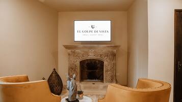 L’intérieur d’un petit hôtel de luxe, avec une cheminée, deux fauteuils en cuir et une table décorative.