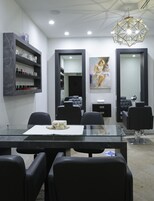 Un'accogliente sala moderna con una scrivania di accoglienza in marmo, poltrone nere e una lampada a sospensione geometrica.