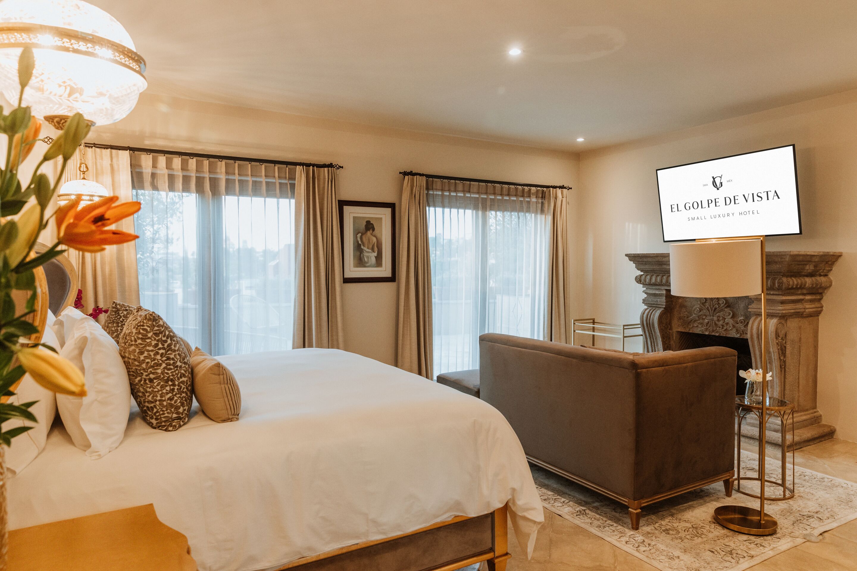Une chambre d’hôtel avec un lit, un canapé, une télévision et une cheminée.
