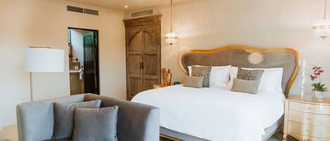 A bedroom with a large bed, a sofa, a nightstand, and a lamp.