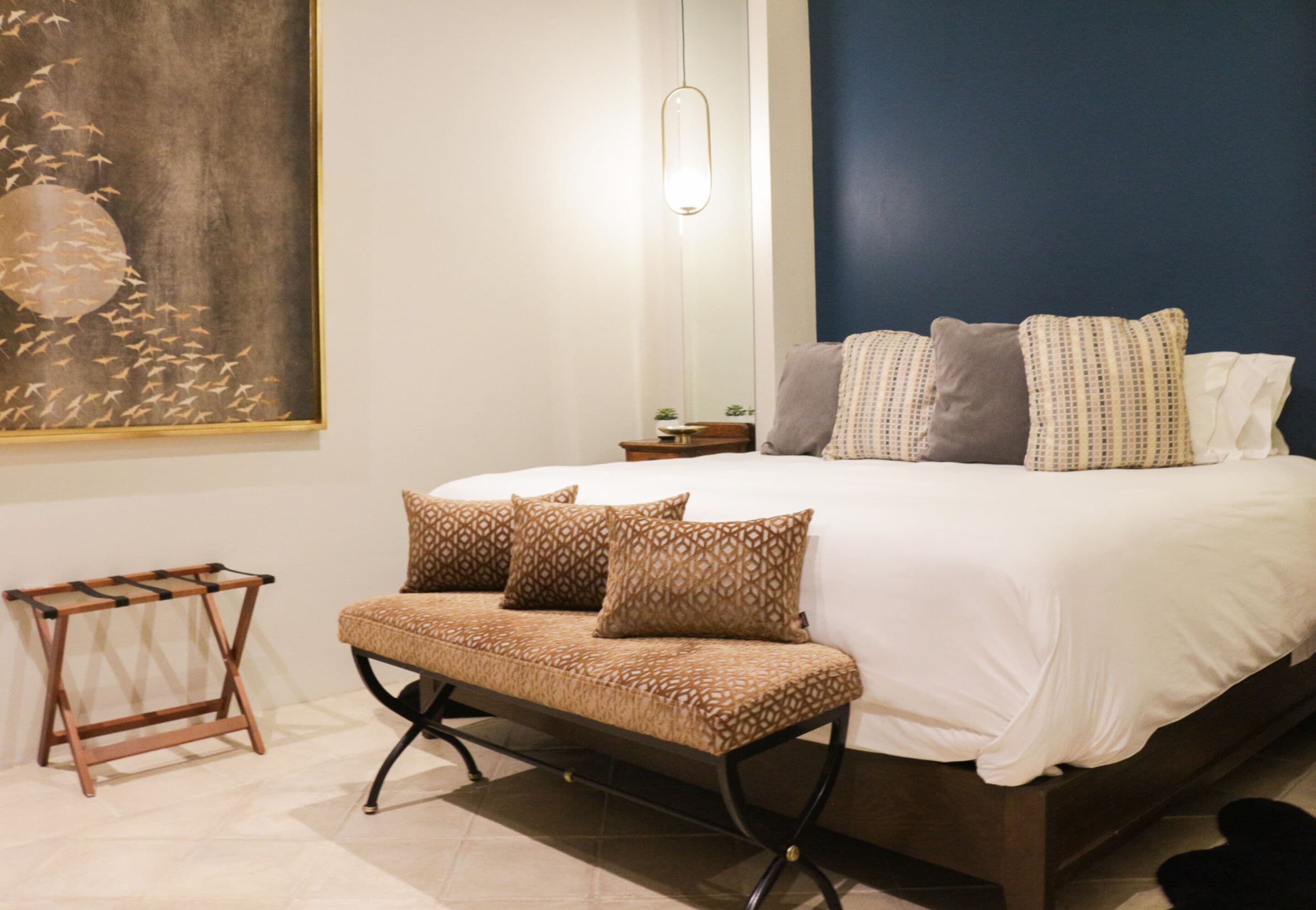 A bedroom with a bed, pillows, a bedside table, and a wall-mounted artwork.