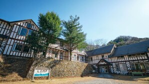 A traditional half-timbered building with a stone wall and a sign reading "LAMP". - Guest House Lamp Bungo Ohno - Hostel (Bungoono)