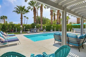 Un área de piscina con sillones reclinables y una pérgola.