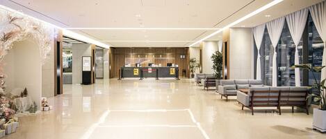 A spacious lobby with a reception desk, seating area, and a Christmas tree.