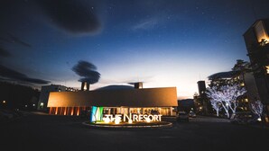 Un edificio moderno con señalización iluminada que dice "THE NRESORT" al anochecer.