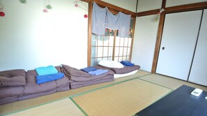 A room with tatami mats, a brown sofa, and a black table. - Nishiogi House Maipenrai (Tokyo)