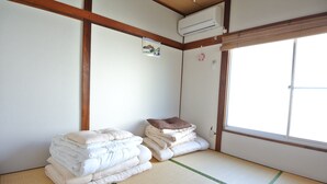 A room with tatami flooring, a stacked bed with pillows, a wall-mounted air conditioner, and a large window with a view. - Nishiogi House Maipenrai (Tokyo)