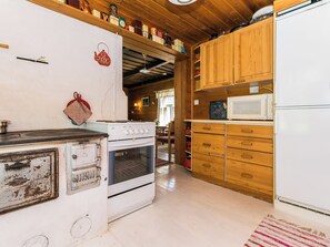 A kitchen with wooden cabinets, a white refrigerator, a stove, and a microwave. - Lamminkangas by Interhome (Saarijärvi)