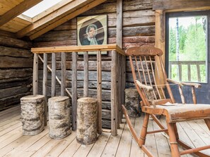 A rustic cabin interior with a wooden rocking chair, a wooden table, and a framed picture on the wall. - Lamminkangas by Interhome (Saarijärvi)