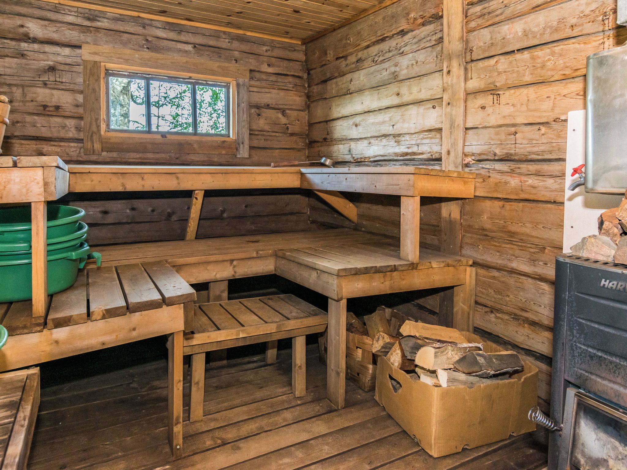 A rustic cabin interior with a wooden bench, a window, and a fireplace.