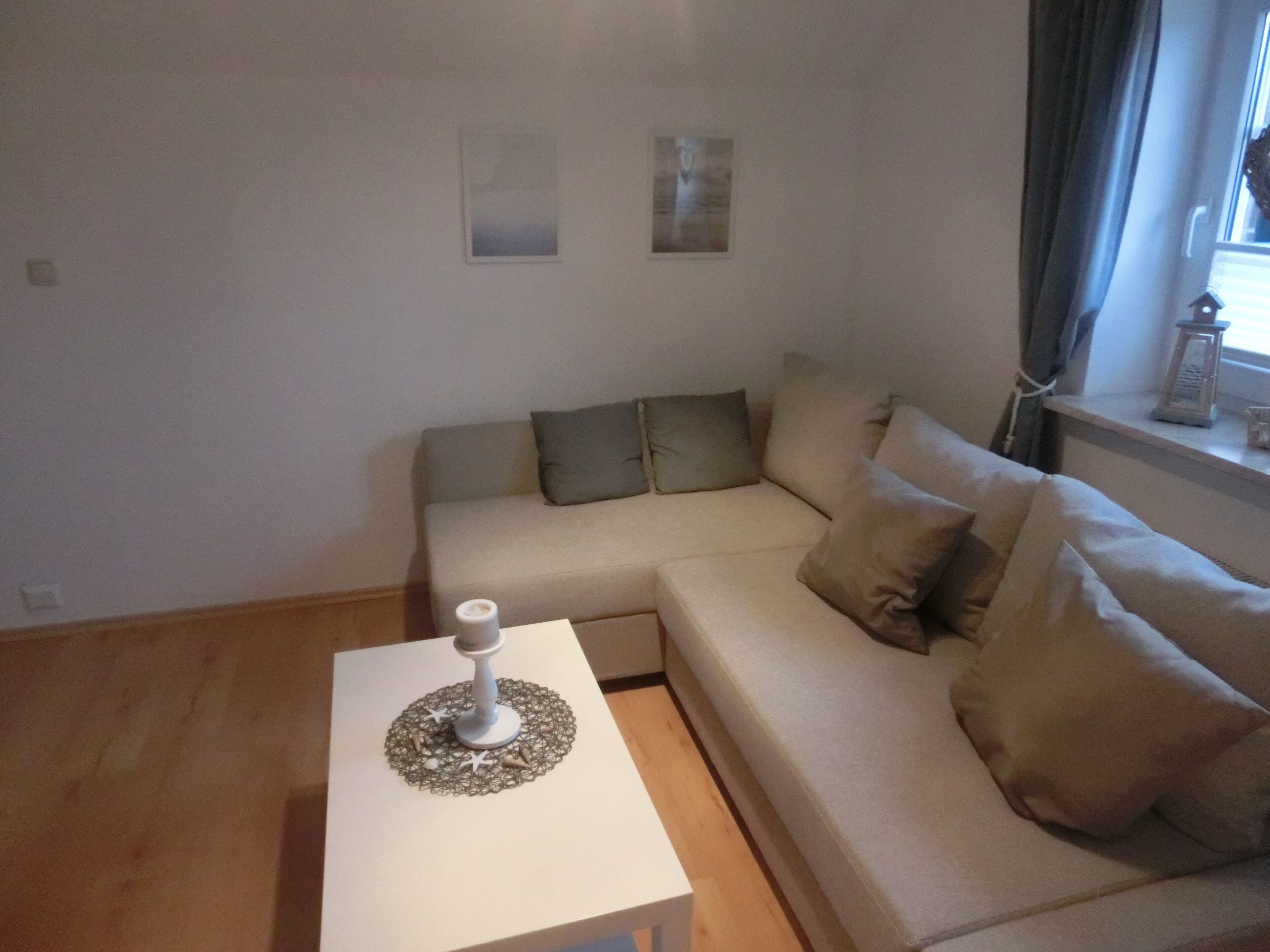 A modern living room with a beige sofa, a white side table, and a small decorative item on the table.